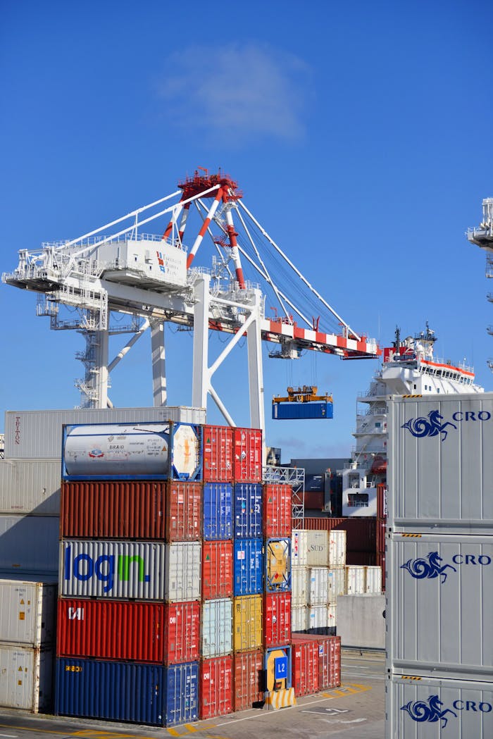 Services Colorful shipping containers stacked in a busy port with cranes overhead.