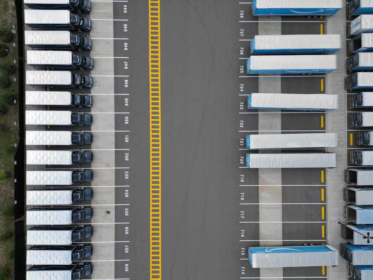 The Art of Drawing Readers In: Your attractive post title goes here Top-down view of lined-up trucks at a logistics parking lot, showing organized transportation hub.